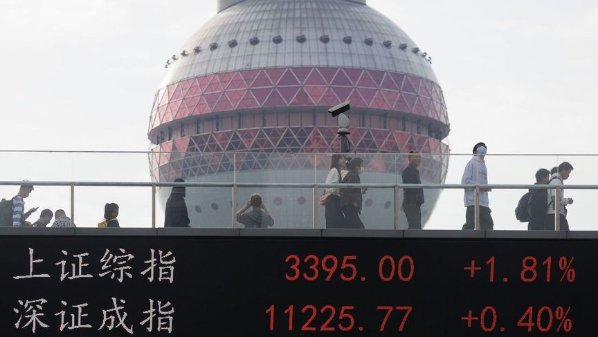 أشخاص يسيرون على جسر مشاة يعرض مؤشرات شنغهاي.